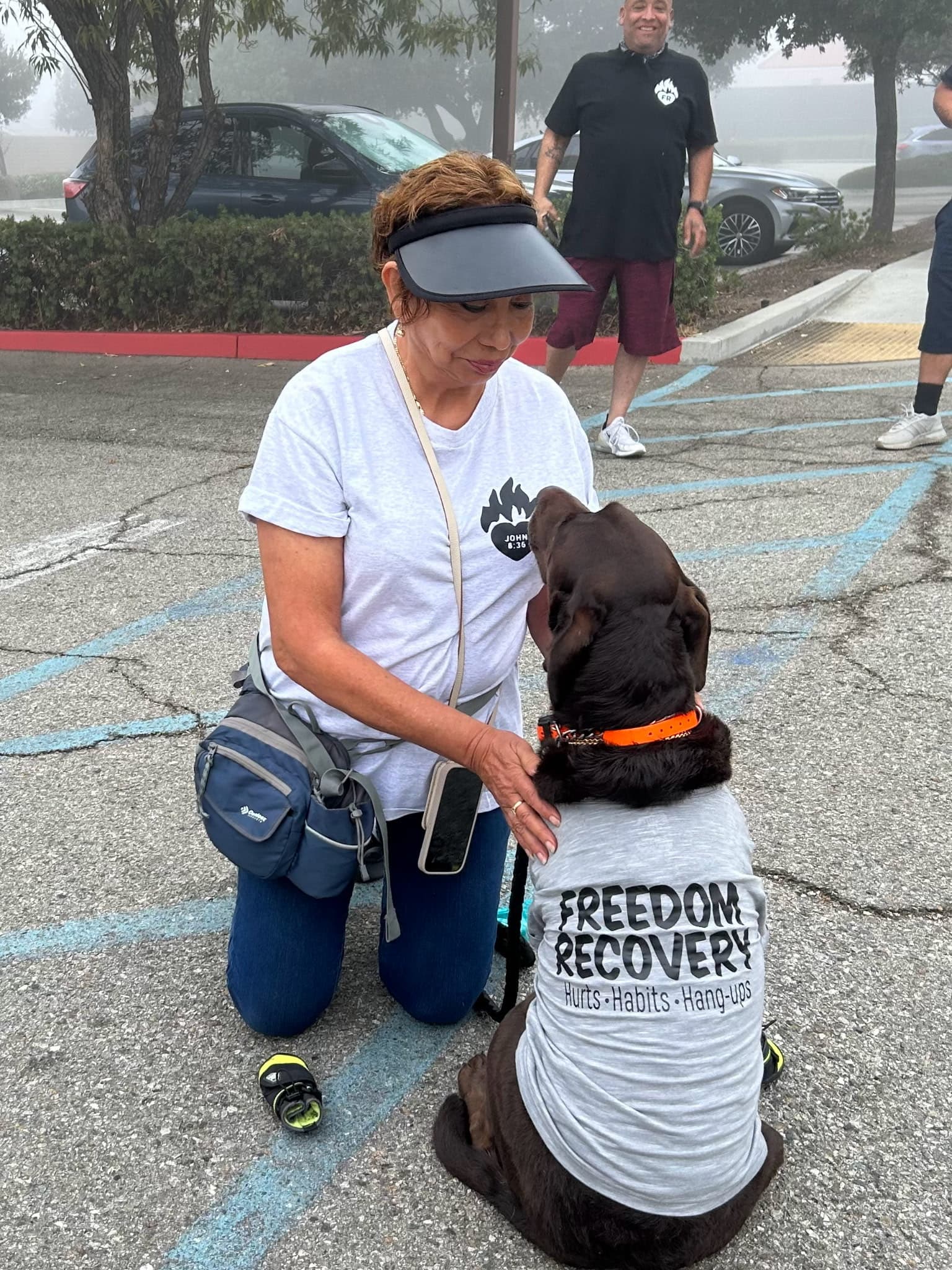 Woman interacting with dog wearing recovery shirt
